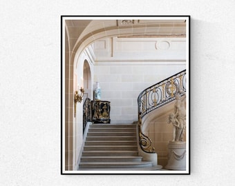 May include: A white and gold ornate staircase with a black wrought iron railing in a grand, white room.