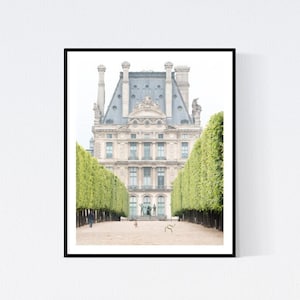May include: A black and white photograph of a building with a symmetrical facade and a grey roof. The building is framed by two rows of green trees.