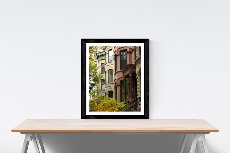 Puede incluir: Una fotograf&iacute;a enmarcada de una fila de edificios de ladrillo con puertas y ventanas de colores. Los edificios est&aacute;n en un entorno urbano y tienen un aspecto vintage. La foto est&aacute; en un marco negro.