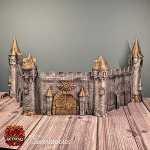 May include: A detailed model of a castle wall with towers and a gate. The castle is primarily gray with gold accents on the towers and gate. The model has a textured appearance, suggesting a stone construction. The logo "FATESEND" is visible.