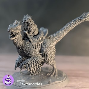 Può includere: Statuetta grigia stampata in 3D di una creatura simile a un raptor con un piccolo animale peloso in groppa. Il raptor ha dettagliate texture di piume e la bocca aperta. La base della statuetta riporta la scritta "extrudables".