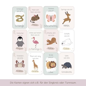 May include: A set of twelve rectangular cards arranged in a grid, each featuring a colorful animal illustration and German text. Animals include a snake, mouse, butterfly, deer, penguin, flamingo, cat, polar bear, crab, giraffe, lion, and turtle.