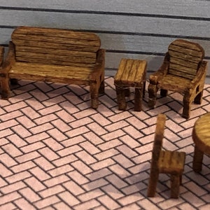 May include: A set of wooden miniature furniture, including a bench, chairs, and tables. The furniture is made of brown wood and has a rustic look. The furniture is arranged on a brick-patterned surface.