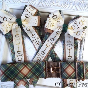 May include: Three brown, white, and gold ribbon bows with a gold equestrian bit design. The bows are attached to a brown, green, and tan plaid ribbon. The ribbon is attached to a brown metal buckle with a gold finish. The text "O' Sew Pretty" is visible at the bottom of the image.