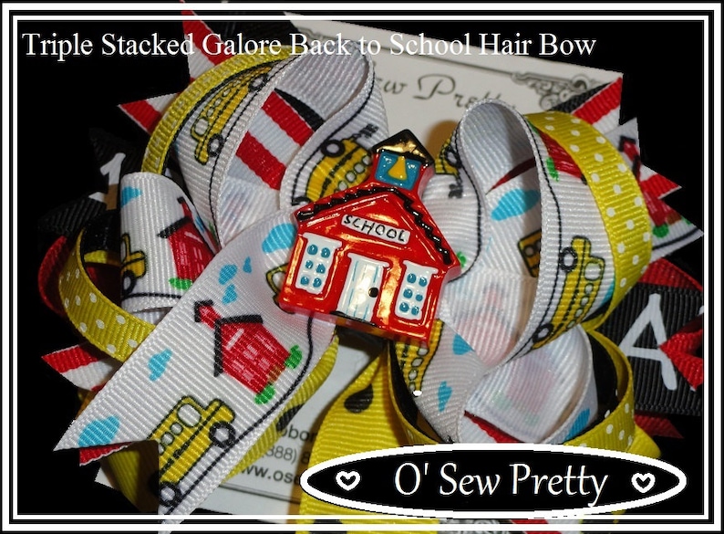 May include: Triple stacked hair bow with a red schoolhouse charm. The bow is made of white, yellow and red ribbon with a polka dot pattern. The ribbon has a school bus and schoolhouse print. The charm has the word "SCHOOL" on the front.