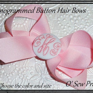 May include: Pink hair bow with a white button featuring a monogram. The bow is made of grosgrain ribbon and has a simple design. The text "O' Sew Pretty" is visible in the bottom right corner of the image.