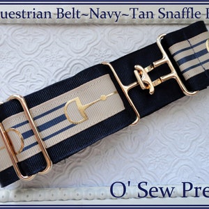 May include: A navy blue and tan equestrian belt with a gold snaffle bit design and a gold buckle. The belt is made of ribbon and has a striped pattern. The text "O' Sew Pretty" is visible in the bottom right corner of the image.