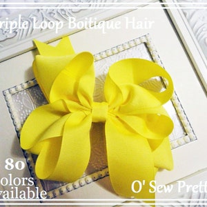 May include: A large yellow triple loop hair bow with the text "O' Sew Pretty" and "80 colors available".