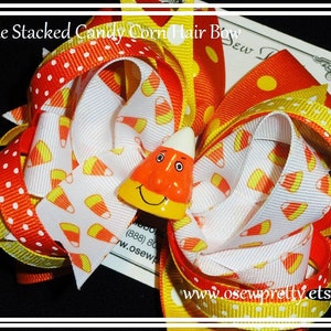 May include: Triple stacked candy corn hair bow with yellow, orange, and white polka dot ribbon. The bow features a candy corn charm with a smiling face.