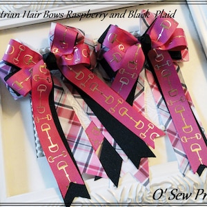 May include: Three pink and black plaid hair bows with gold equestrian stirrup accents. The bows are tied with black ribbon and have the text "DIT DIG DIC" printed on them.