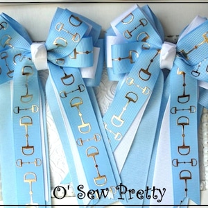 May include: Several light blue hair bows with gold horse bit designs. The bows have white accents and long ribbons. The text "O' Sew Pretty" is at the bottom of the image.
