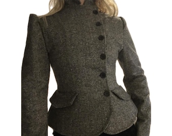 May include: A grey tweed jacket featuring a high collar, long sleeves, and a side-button closure with six dark buttons. The garment includes two small hip pockets and a peplum-style hem. The text SKY.STAR SIGNS ARTISAN ATELIER AMSTERDAM and XS-XL appear.