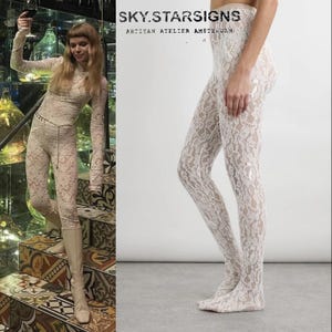 Peut inclure: Collants en dentelle blanc cassé. Les collants présentent un motif de dentelle floral délicat. Le texte "SKY.STARSIGNS ARTISAN ATELIER AMSTERDAM" est visible dans le coin supérieur droit. Le modèle porte les collants.
