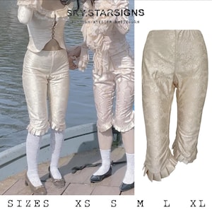 Może przedstawiać: Spodnie w kolorze kremowym z kwiatowym wzorem i falbankami u dołu. Spodnie są pokazane na modelce, a także jako płaskie ułożenie. W obrazie widoczny jest tekst "SKY.STAR SIGNS".
