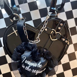 May include: Black heart-shaped handbag with a silver chain and a black heart-shaped charm that says "I wanna be in the sequel".