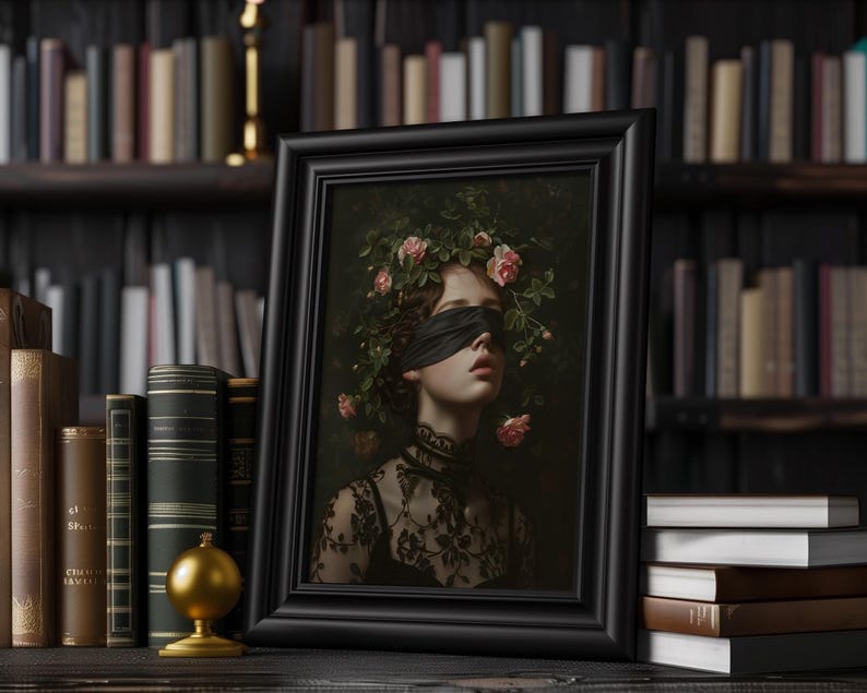 A framed portrait of a woman with a black blindfold and a floral crown. The artwork is in a black frame, set against a backdrop of bookshelves filled with books. The portrait features a dark, romantic aesthetic.