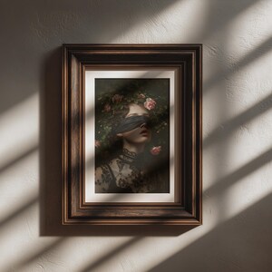 May include: A framed art print depicting a woman with a blindfold and floral headpiece. The artwork has a dark, romantic aesthetic, highlighting the woman's face and the intricate details of her clothing. The frame is a dark brown colour.