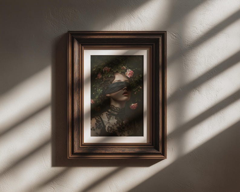 May include: A framed art print depicting a woman with a blindfold and floral headpiece. The artwork has a dark, romantic aesthetic, highlighting the woman's face and the intricate details of her clothing. The frame is a dark brown colour.