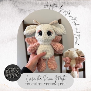 May include: A crocheted pixie moth toy in cream and pink. The moth has large black eyes, pink wings, and is held by a hand. The text "Liora the Pixie Moth CROCHET PATTERN | PDF" is displayed below the moth.