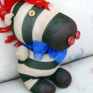 May include: A handmade zebra toy made from striped socks with a red yarn mane, blue ribbon, and button eyes.