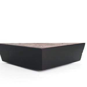 May include: A black triangular wooden furniture leg.