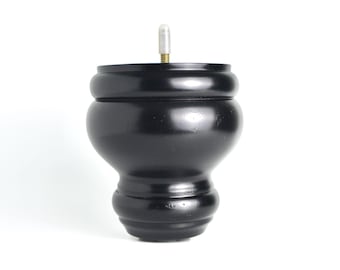 Könnte beinhalten: Schwarzes Möbelbein aus Holz mit abgerundeter Oberseite und einem Gewindeeinsatz aus Metall. Das Bein ist etwa 10 cm hoch.