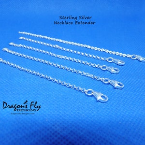 K&ouml;nnte beinhalten: F&uuml;nf silberne Kettenverl&auml;ngerungen auf blauem Hintergrund. Die Verl&auml;ngerungen bestehen aus einer zarten Kette mit einem Karabinerverschluss. Der Text "Sterling Silver Necklace Extender" befindet sich oben im Bild. Der Text "Dragonfly Designs" befindet sich unten im Bild.