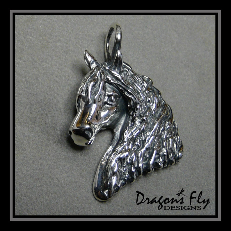 May include: Silver pendant featuring a detailed, three-dimensional sculpture of a horse's head. The horse's mane is textured and flowing. The pendant has a loop at the top for attaching a chain.
