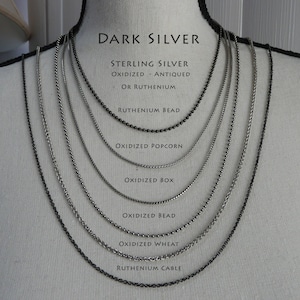 May include: A display of nine different sterling silver chains in various styles, including bead, box, popcorn, wheat, and cable. The chains are all oxidised and have a dark silver finish. The text "DARK SILVER" is at the top of the image, and the names of each chain are listed below them.