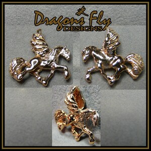 May include: Three gold-coloured winged horse charms, each with a different pose. The charms are on a grey background with the text "Dragons Fly Designs" above them.