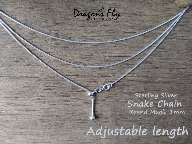K&ouml;nnte beinhalten: Eine Halskette mit Schlangenkette aus Sterlingsilber mit verstellbarer L&auml;nge. Die Halskette hat drei Str&auml;nge aus zarten, runden 1-mm-Ketten. Der Text "Adjustable length" ist unten im Bild zu sehen.