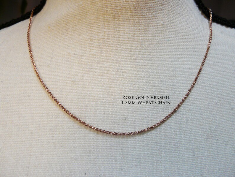 May include: A rose gold vermeil 1.3mm wheat chain necklace on a white fabric background.