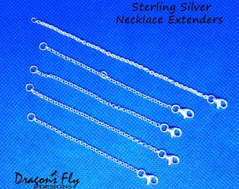 May include: Five sterling silver necklace extenders of varying lengths on a blue background. The extenders are made of a delicate chain with a lobster clasp.