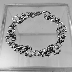 May include: A silver bracelet with a chain design featuring multiple horse figures. The bracelet has a clasp closure.
