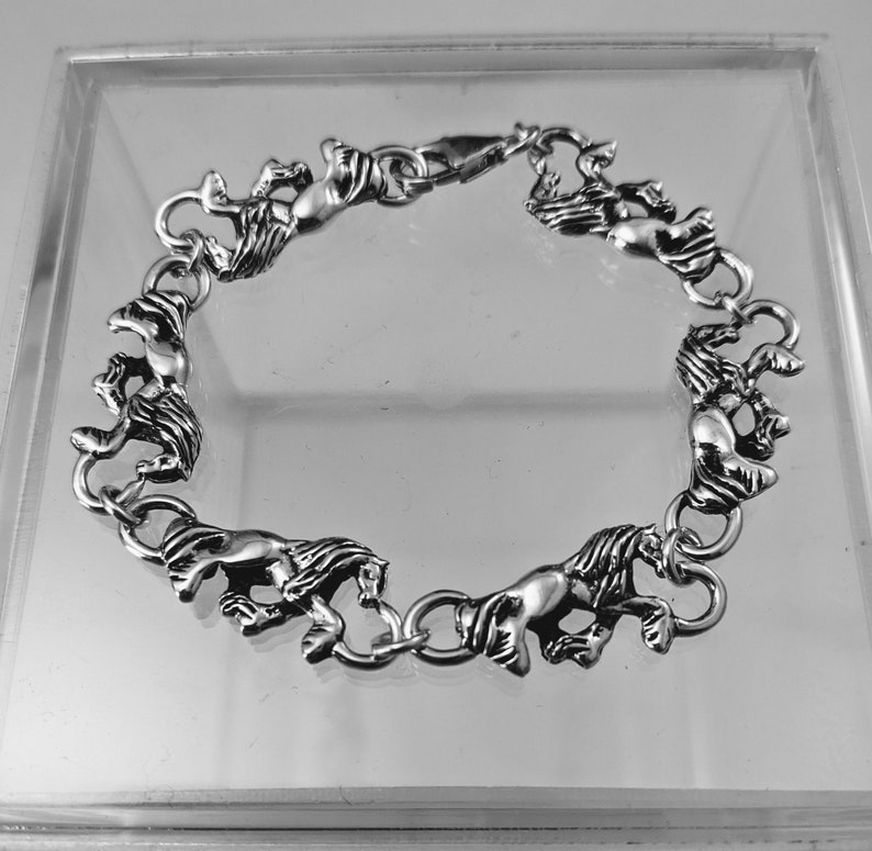 May include: A silver bracelet with a chain design featuring multiple horse figures. The bracelet has a clasp closure.