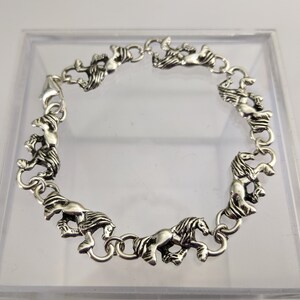 May include: A silver bracelet with a chain made of horse head links.