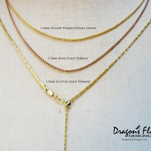 May include: Three gold chains of different widths and styles, labelled 1.3mm Yellow Vermeil Wheat Chain, 1.3mm Rose Gold Vermeil, and 1.5mm Glitter Gold Vermeil. The chains are displayed on a beige fabric background.