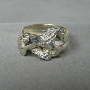 May include: A silver ring with a detailed design of a horse running. The ring is made of two bands, one on top of the other.