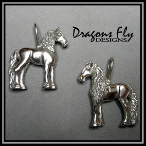 May include: Two silver horse charms with a flowing mane and tail. The charms are detailed and have a shiny finish. Dragons Fly Designs is printed on the background.