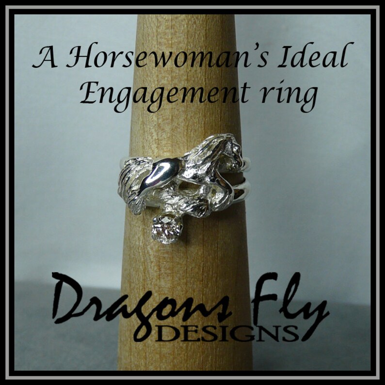 May include: A silver ring featuring a sculpted horse design with a single diamond set in the center. The ring is displayed on a wooden ring holder. The text "A Horsewoman's Ideal Engagement ring" is displayed above the ring and "Dragon Fly DESIGNS" is displayed below the ring.