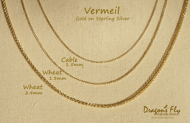May include: Three gold chains of different widths and styles, labelled "Wheat 2.4mm", "Wheat 1.3mm", and "Cable 1.5mm". The chains are on a beige fabric background. The text "Vermeil Gold on Sterling Silver" is at the top of the image. The text "Dragon's Fly Designs" is at the bottom of the image.