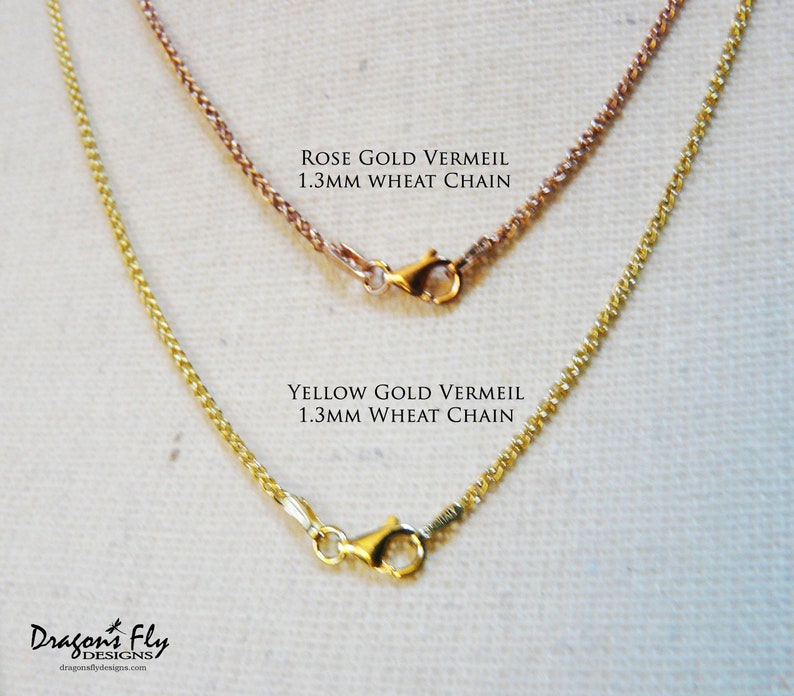 May include: Two gold chains, one rose gold and one yellow gold, both 1.3mm wheat chains. The chains are displayed on a white fabric background.