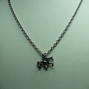 May include: A silver chain necklace with a pendant of a winged horse, or pegasus, in flight.