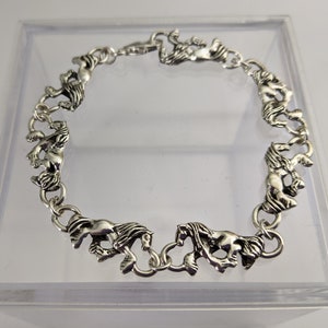 May include: Silver bracelet with a chain of linked horse figures.