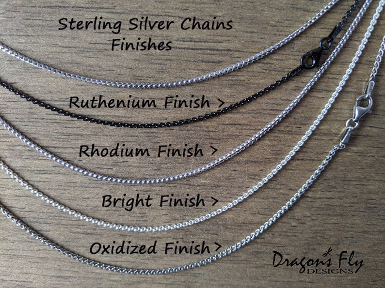 May include: Five sterling silver chains in different finishes: oxidised, bright, rhodium, ruthenium, and black. The chains are laid out on a wooden surface. Sterling Silver Chains Finishes Ruthenium Finish > Rhodium Finish > Bright Finish > Oxidised Finish > Dragon's Fly DESIGNS