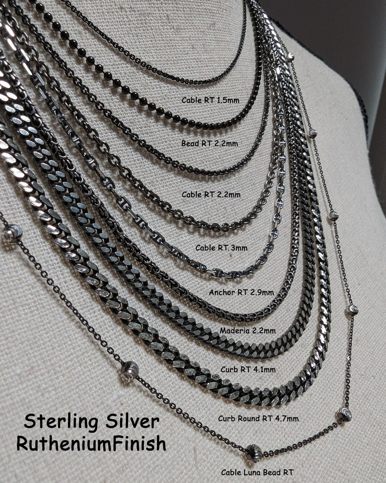 K&ouml;nnte beinhalten: Eine Auswahl an Sterling-Silberketten mit einer Ruthenium-Beschichtung. Die Ketten sind auf einem Mannequin ausgestellt und mit ihren Namen und Gr&ouml;&szlig;en in Millimetern beschriftet. Die Ketten umfassen Cable RT 1,5 mm, Bead RT 2,2 mm, Cable RT 2,2 mm, Cable RT 3 mm, Anchor RT 2,9 mm, Maderia 2,2 mm, Curb RT 4,1 mm, Curb Round RT 4,7 mm und Cable Luna Bead RT.