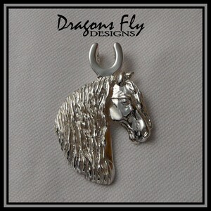 May include: Silver horse head pendant with a horseshoe charm. The pendant is detailed with a textured mane and a realistic horse head.