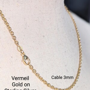 May include: A gold vermeil cable chain necklace on a white background. The chain is 3mm wide and is made of sterling silver with a gold plating. The text "Vermeil Gold on Sterling Silver" and "Cable 3mm" is visible in the image.