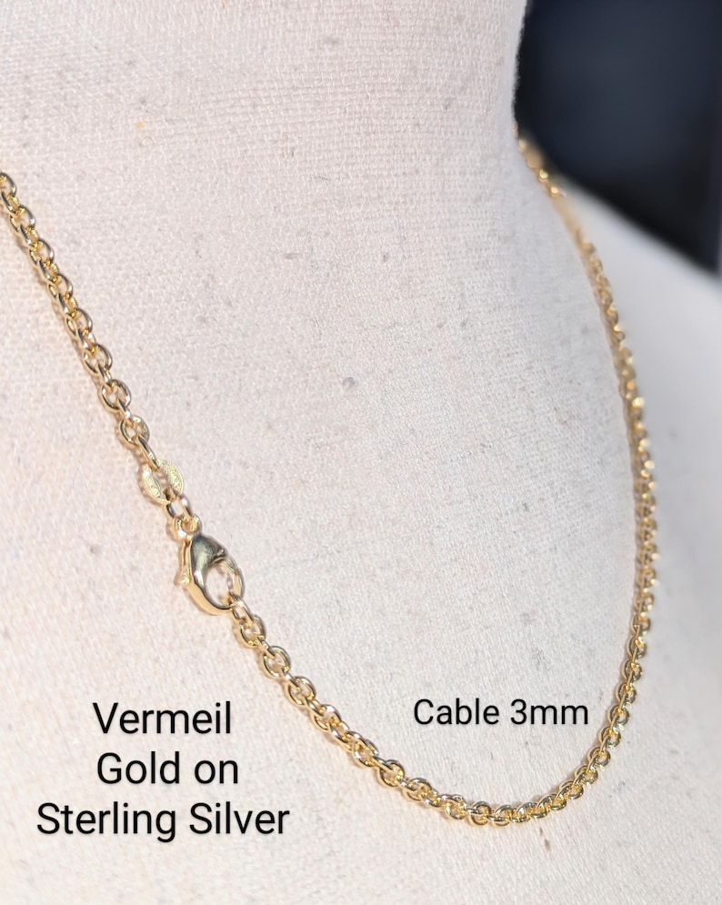 May include: A gold vermeil cable chain necklace on a white background. The chain is 3mm wide and is made of sterling silver with a gold plating. The text "Vermeil Gold on Sterling Silver" and "Cable 3mm" is visible in the image.