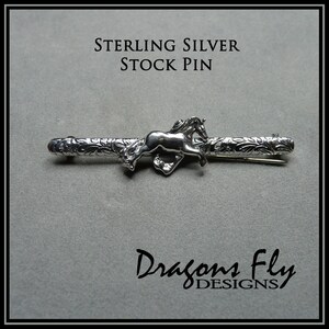 May include: Sterling silver stock pin featuring a detailed design of a horse running through a floral pattern. The pin is made by Dragons Fly Designs.